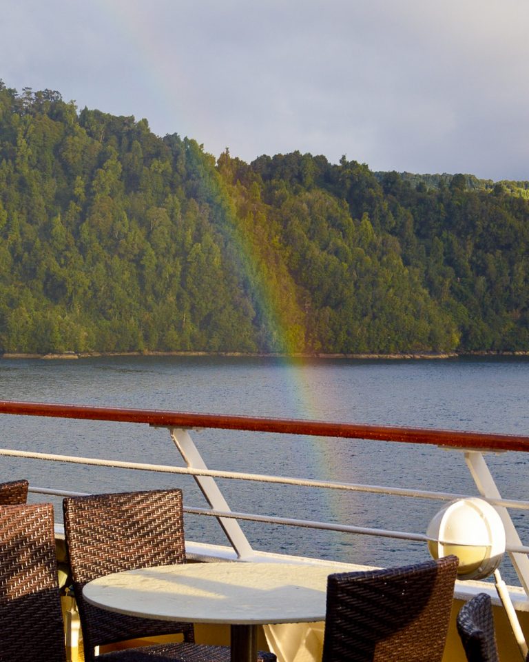 Arco-íris ao lado do deck de navio, em um fjord chileno