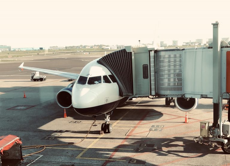 Avião parado em aeroporto, com finger de acesso.