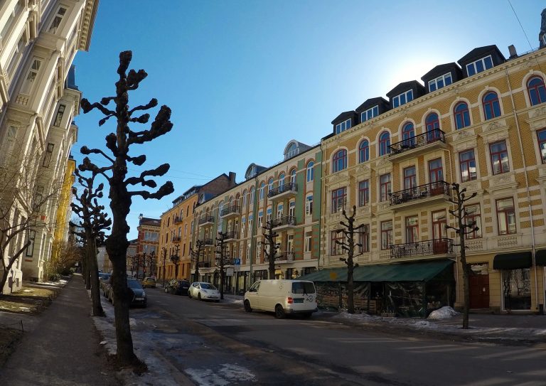 Casas antigas e árvores sem folhas em rua vazia de Oslo.